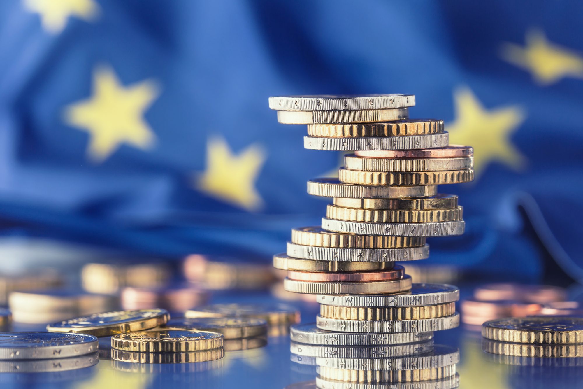 Euro coins in front of the EU flag